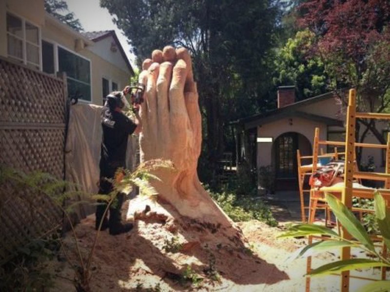 Mann fertigt mit Motorsäge große Menschenhand aus Holz